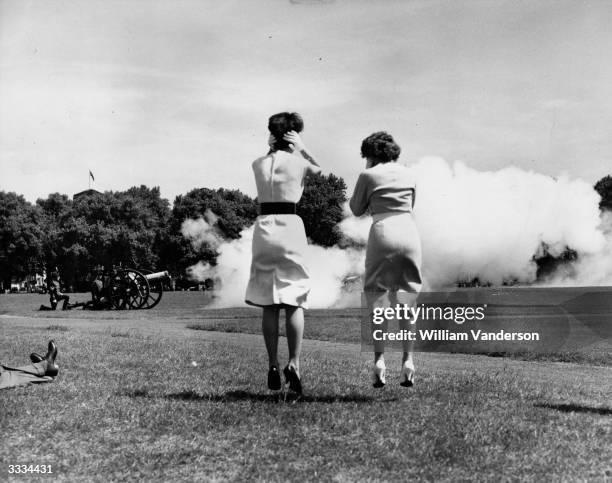 Two London office workers clasp their hands over their ears and jump in the air as the guns of the King's Troop Royal Horse Artillery fire their...