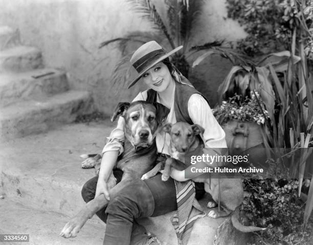 American silent screen actress Irene Rich sitting with two dogs in a scene from the film 'The Climbers', directed by Paul L Stein for Warner Brothers.