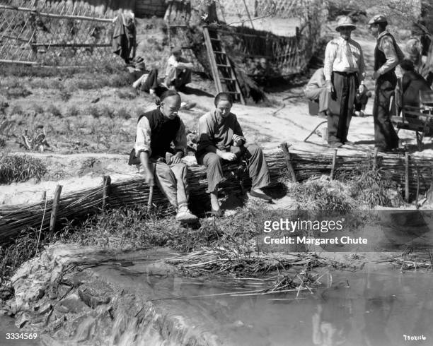 American actor Paul Muni and actress Luise Rainer prepare to shoot a farm scene for the film 'The Good Earth'.