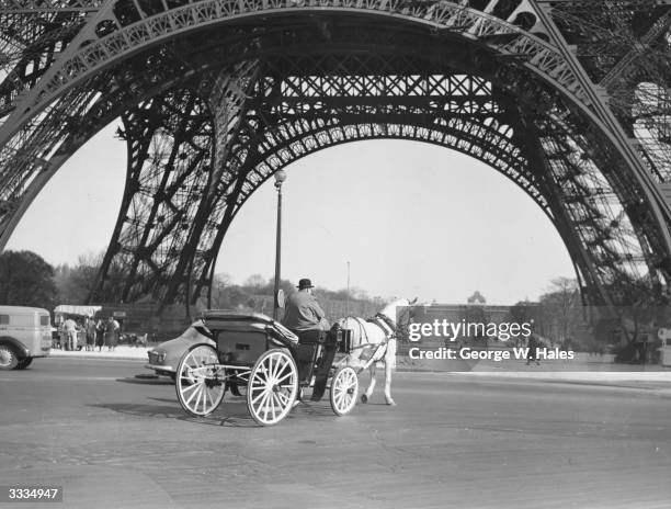 Horse and carriage passing by the Eiffel Tower.