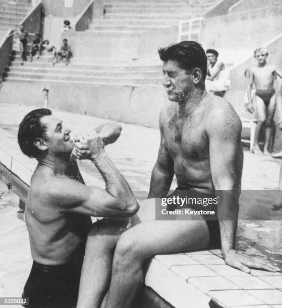 Tarzan star and Olympic swimmer Johnny Weissmuller sprays French swimming champion Alex Jany with water after taking a swim in Tourelles swimming...