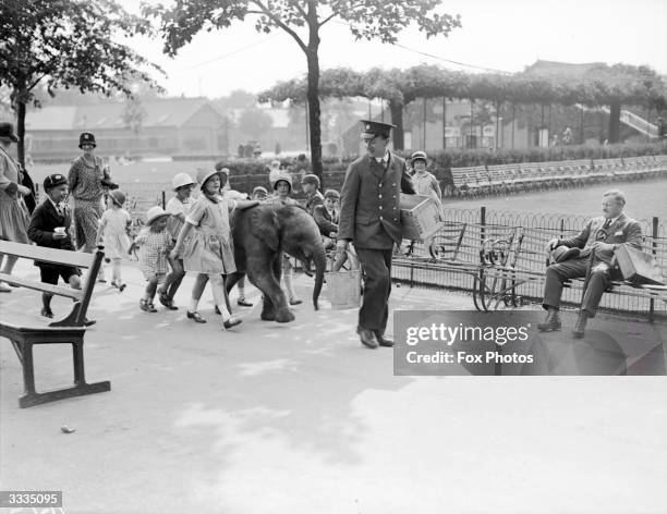 Visitors help the keeper at London Zoo with Peter the baby elephant at teatime.