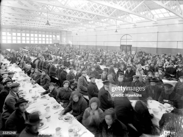Large group of immigrants sitting down to dinner at the Atlantic Park Hostel in Eastleigh, Hampshire, March 1924. The hostel is mainly used by...