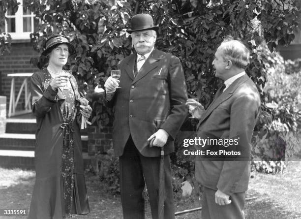 English composer, Sir Edward Elgar enjoying a drink in a garden with friends.