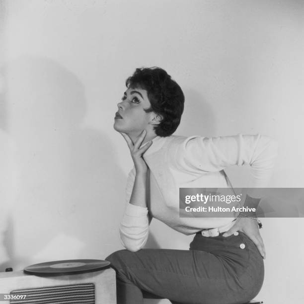 Miss Love, a fashionable young woman, sits listening to a record being played on the gramophone.