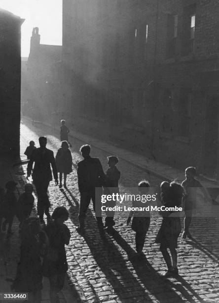 Children walking down a cobbled street in Birkenhead, Merseyside, north-western England. Original Publication: Picture Post - 1746 - Planning Post...