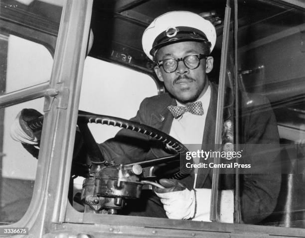 West-Indian London Transport bus driver at the wheel of his RT bus, Peckham Bus Garage, south London, September 1958. His PSV licence badge is number...