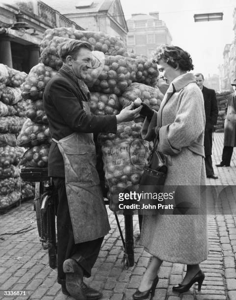 Muriel Young, commercial television's announcer, passes through Covent Garden Market on her way to work, where she stops to chat with some of the...