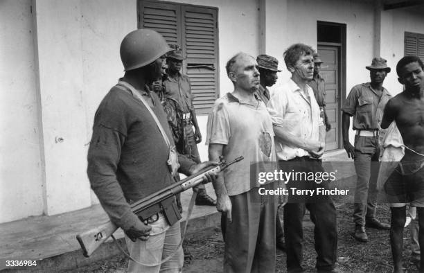 John Downing-Tractor, a company rep, and William Blakeley, a marine manager, under guard by Nigerian Federal troops who took them hostage when they...