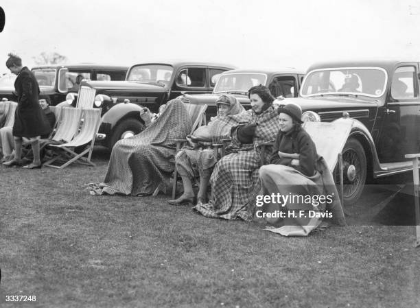 Victor Cubitt, Desmond Cubitt, Diana Burke and Rowena Burke wrap up against the cold whilst watching the Polo match between kent and Sussex at...