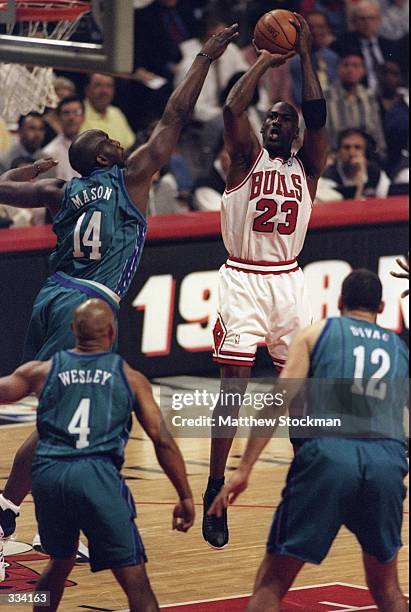 Michael Jordan of the Chicago Bulls jumps to shoot the basket as Anthony Mason of the Charlotte Hornets tries to block at the United Center in...