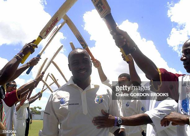 West Indies captain Brian Lara walks under an arch of bats 12 April, 2004 as teammates congratulate him on his record breaking 385 on the third day...