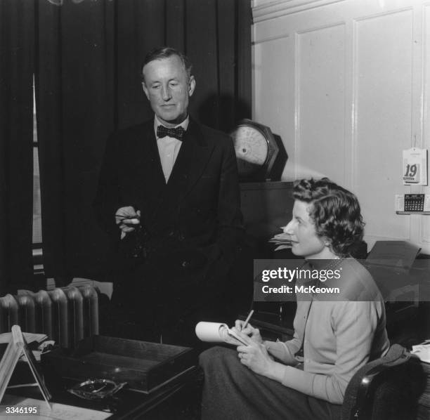 English novelist Ian Fleming , best known for the character James Bond, dictating to his secretary in his study.