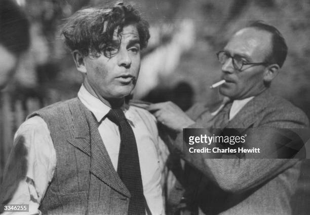 Welsh film director and actor Emlyn Williams , left, being helped on with his jacket after a fight scene in his film 'The Last Days Of Dolwyn'....