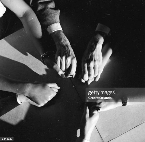 Group of occultists holding hands during a seance.