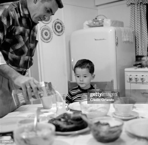 Jimmy Blake, the adopted Japanese-American son of American serviceman James Blake watches his father pour him one of his first glasses of milk at...