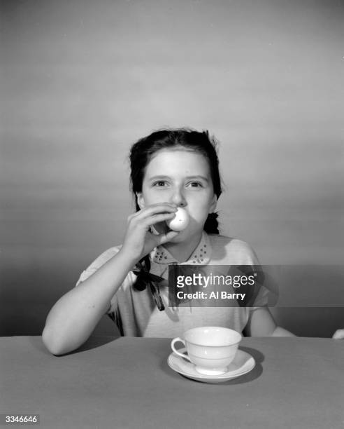 Young girl blowing an egg to remove the contents before decorating it for Easter.