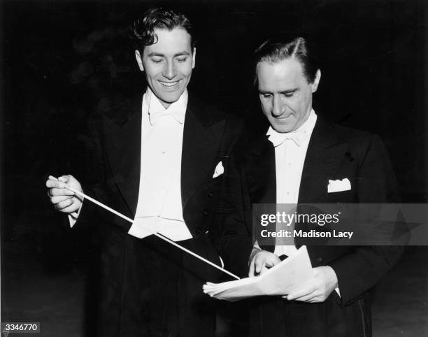 Actor Jeffrey Lynn receiving instructions from conductor Acadie Konchester during the filming of the Warner brothers film 'Four Wives'.