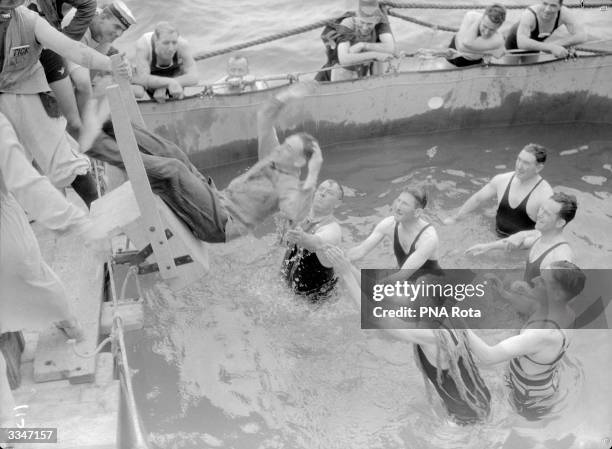 The Duke of Gloucester amongst a group preparing to catch and duck a falling victim, part of the ceremony of 'crossing the line' as their ship the...