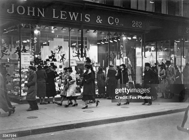 Passers-by outside John Lewis and Co's department store in Oxford Street, London, where there is a window display for Christmas gifts.