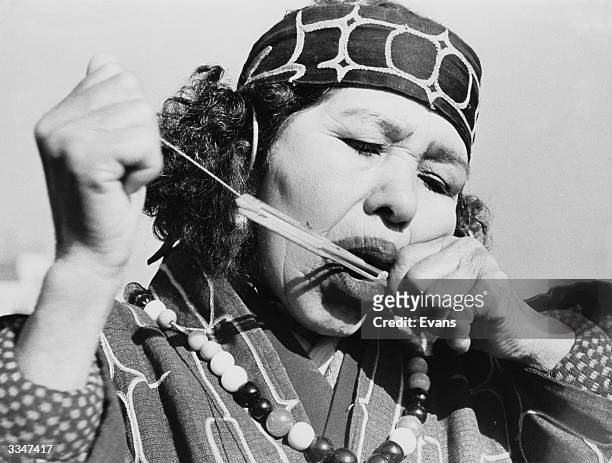 An Ainu tribeswoman holding a group of threads to her mouth.