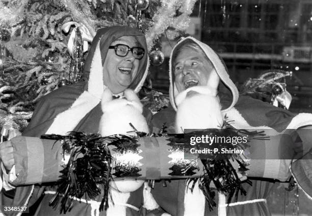 Popular British comedians Eric Morecambe and Ernie Wise pull a Christmas cracker whilst dressed up as Santa.