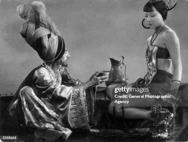 The evil associate played by Snitz Edwards discusses the Princess with Anna May Wong in 'The Theif Of Bagdad' a flamboyant silent film which borrows...