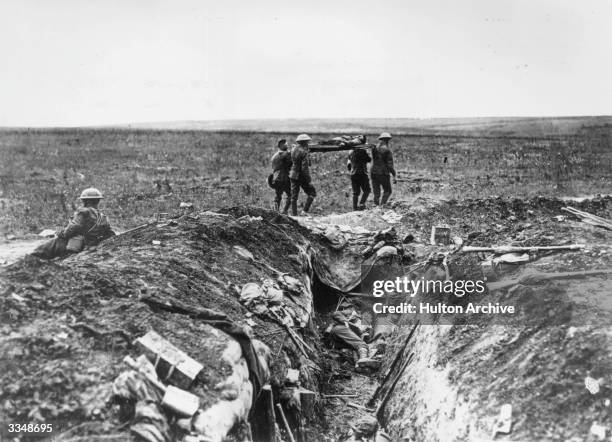 Wounded British soldier is stretchered back to camp past a carnage-strewn trench, during the First World War.