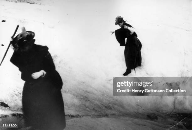 Two long skirted women descend into a crevasse on the 'Mer de Glace'.