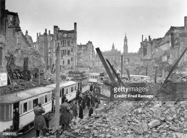People getting on trams in the midst of the ruins left by an Allied air raid on Johannstrasse, Dresden, in the Soviet zone of Germany after the...