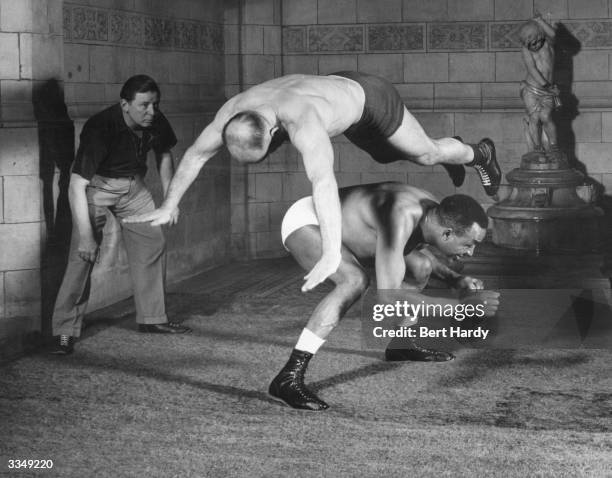 Canadian wrestler and former Empire heavyweight boxing champion Larry Gains ducks as his partner hurtles over him during a training bout at the...