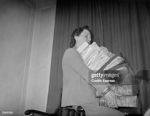 Woman holding a large pile of files and papers.