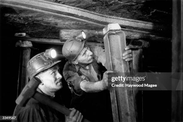 Two coal miners working to secure a shaft prop at the Cwm Gorse Colliery, Pontypridd in Wales. Original Publication: Picture Post - 8444 - Coal...