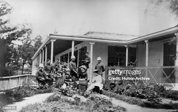 Group of British expatriots, some in military uniform, sitting outside their house in India.