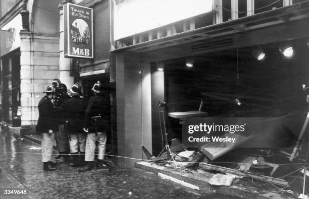 Firemen survey the damage outside the Birmingham pub, 'Tavern in the Town', after an IRA bomb blast.