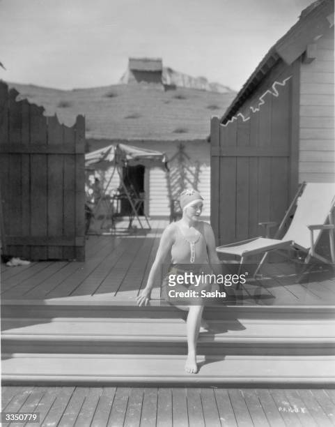In a swimsuit and swimcap, silent film star Pauline Frederick on the steps of her beach bungalow.