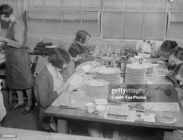 Women painting decoration on to plates by hand at the Wedgwood pottery, Stoke On Trent, Staffordshire.