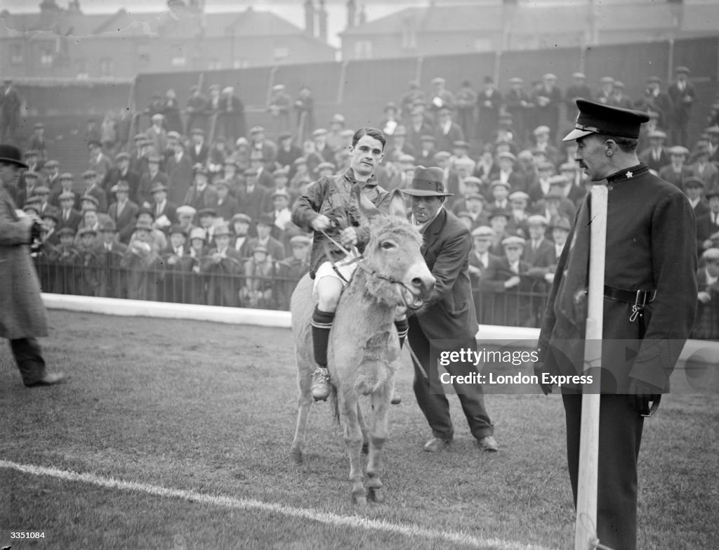 English jockey Sir Gordon Richards riding a donkey at the start of ...