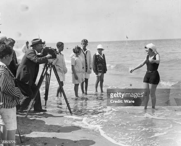 Woman being filmed by cine camera as she paddlles in the sea on a beach at Deauville, Calvados, France.