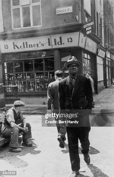 West Indian immigrant walks past Greek Street in Soho, London. Original Publication: Picture Post - 4825 - Is There A British Colour Bar - pub. 1949