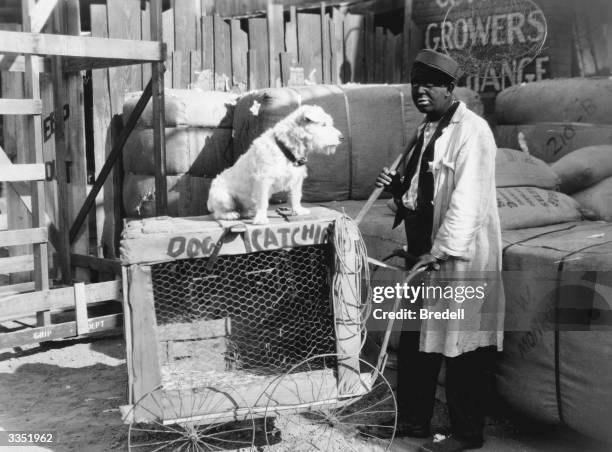 White American minstrel comedian Charles Mack with an improvised mobile kennel and catching net in a scene from the film 'Two Black Crows In The AEF'.