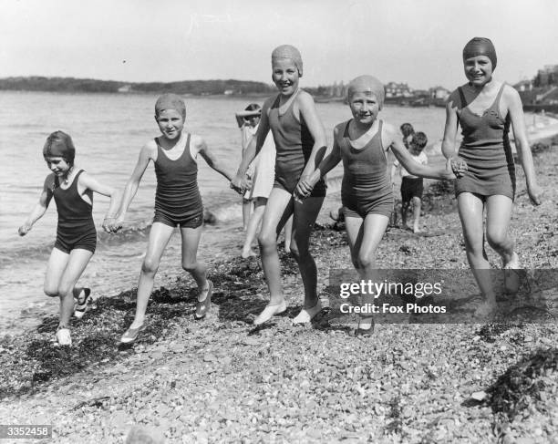 Group of young friends run along the beach in the sunshine in Bangor.