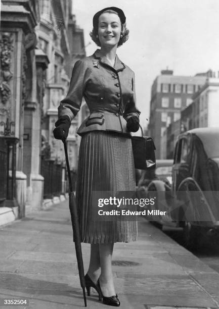 Jean Dawnay, famous fashion model for the House of Dior, wearing 'Black Diamond', an acetate brocade suit in London, before leaving for the races at...