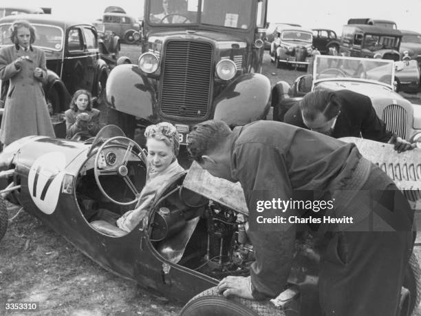 Woman racing driver, Mrs Cook having the rear-mounted engine of her car checked in the car park at Brands Hatch. Original Publication: Picture Post -...