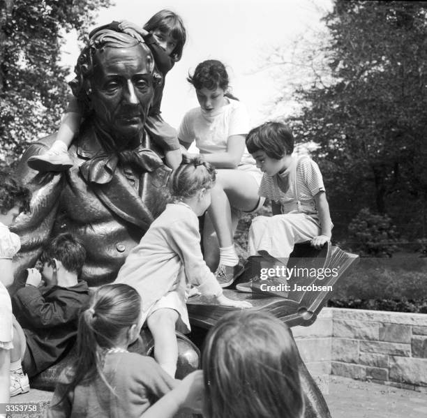 Group of children waiting for a story reading sitting on the statue of fairy story writer Hans Christian Andersen in Central Park, New York.