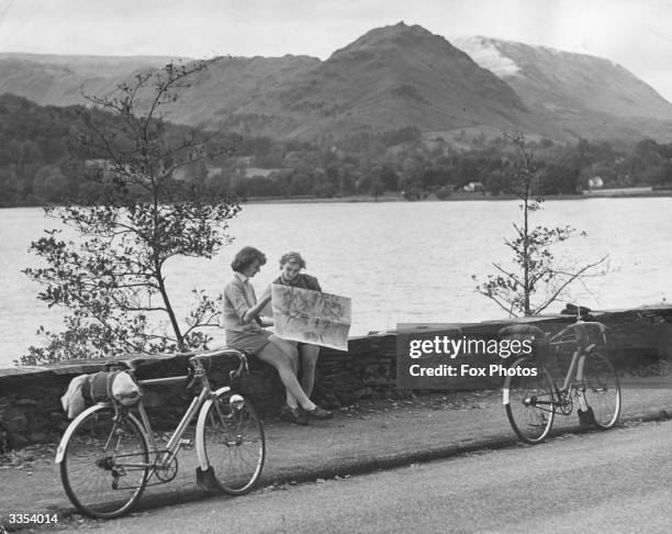 Margaret Blackburn and Vera Thompson resting to consult the map next to Grasmere during an Autumn holiday in the Lake District, Cumbria.