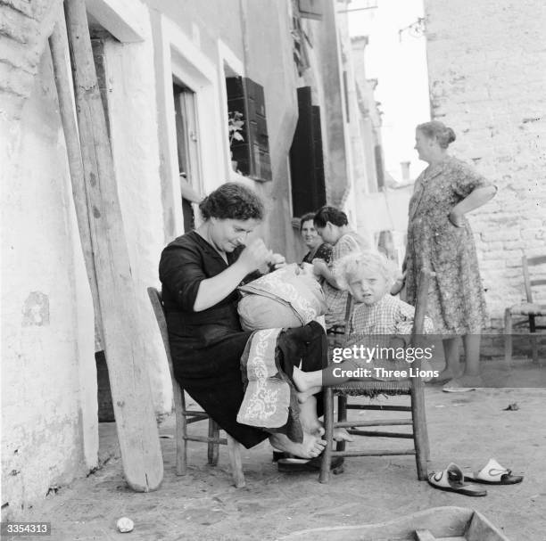 Outside their houses on the island of Burano, Venice, busy mothers make lace and mind their children at the same time.