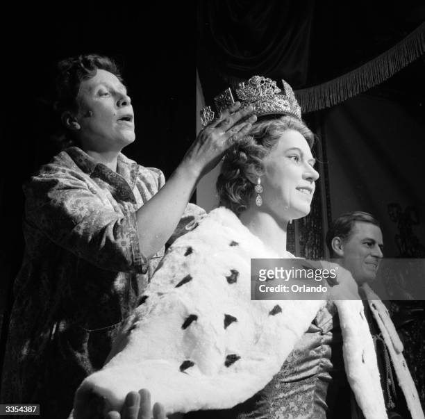 Replica of Queen Elizabeth II's crown being fitted to her waxwork effigy at Madame Tussaud's waxworks museum, London.