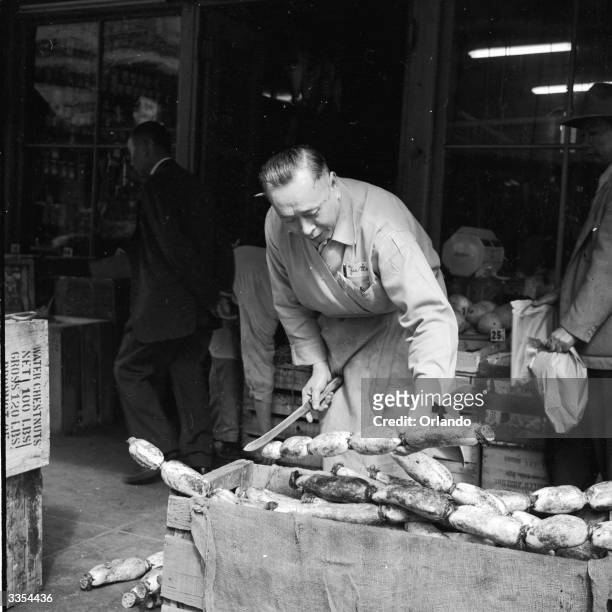 Stallholder at the Yee Wo market in Chinatown, San Francisco, slices off a section of lotus root for a customer. The large knobbly root is imported...