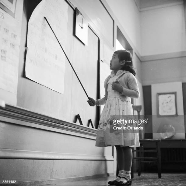 Little Chinese girl reads aloud from the board during an English class at the Commodore Stockton School in Chinatown, San Francisco. The school...